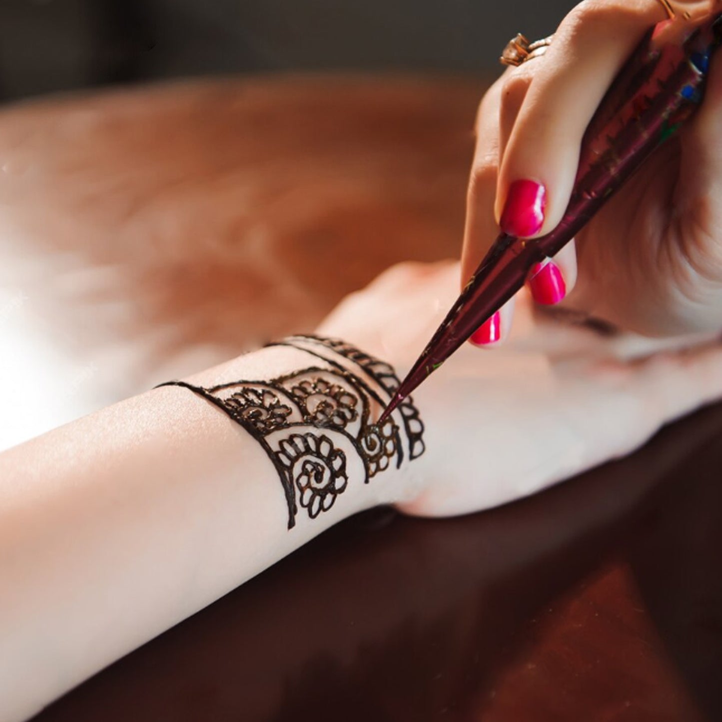 Close-up of Freegrin henna cone application. Drawing a precise and beautiful temporary Mehndi tattoo design on the wrist