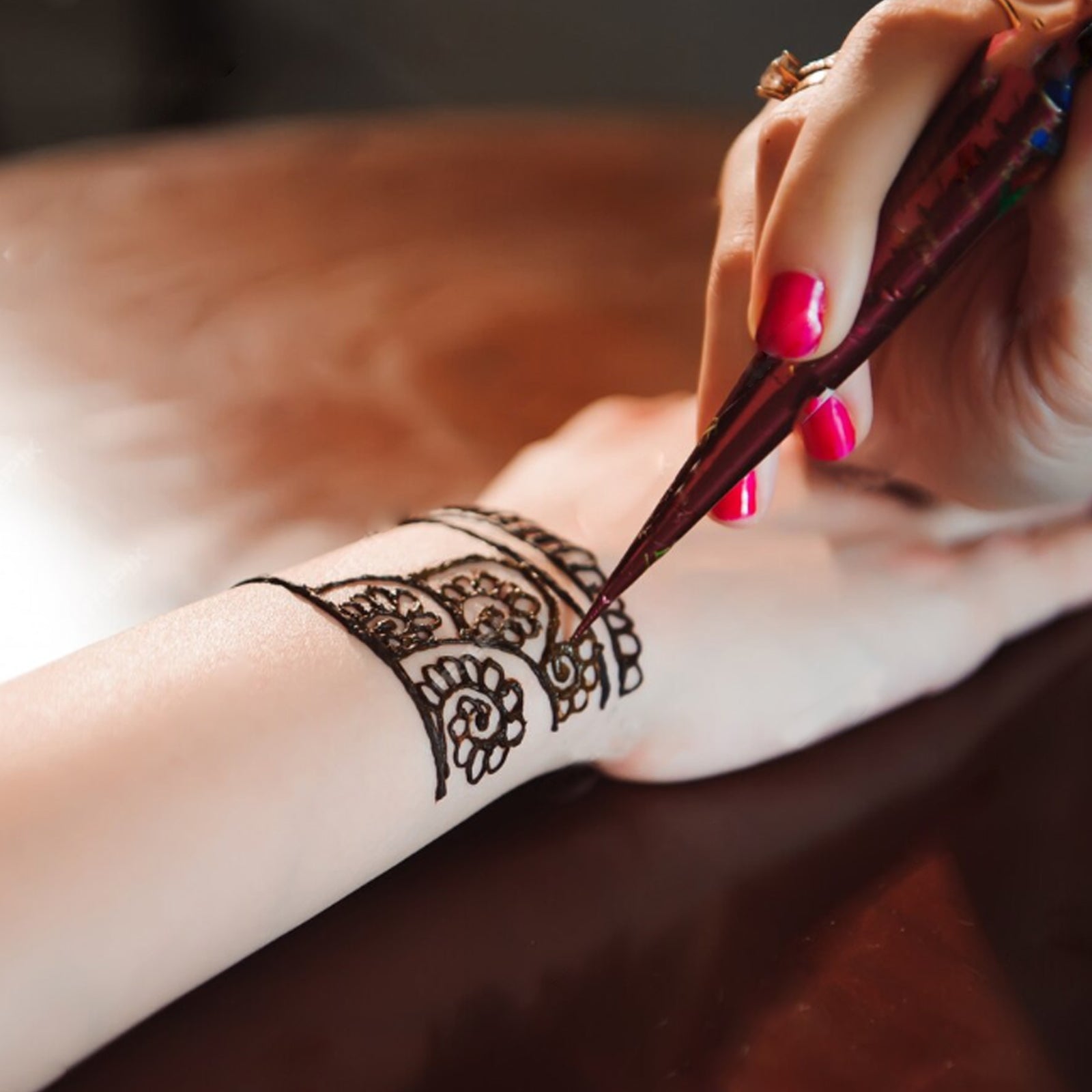 Close-up of Freegrin henna cone application. Drawing a precise and beautiful temporary Mehndi tattoo design on the wrist